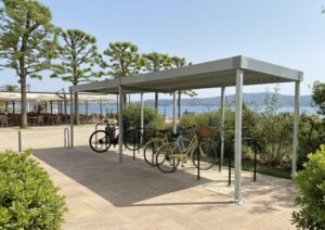 Abri vélo ouvert installé en bord de mer avec plusieurs vélos stationnés, offrant une solution pratique et résistante pour les zones touristiques ou urbaines.