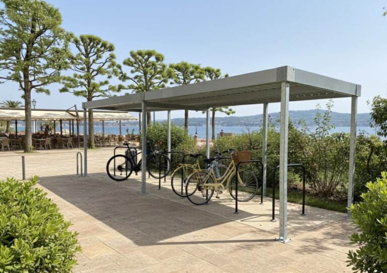 Abri vélo ouvert installé en bord de mer avec plusieurs vélos stationnés, offrant une solution pratique et résistante pour les zones touristiques ou urbaines.