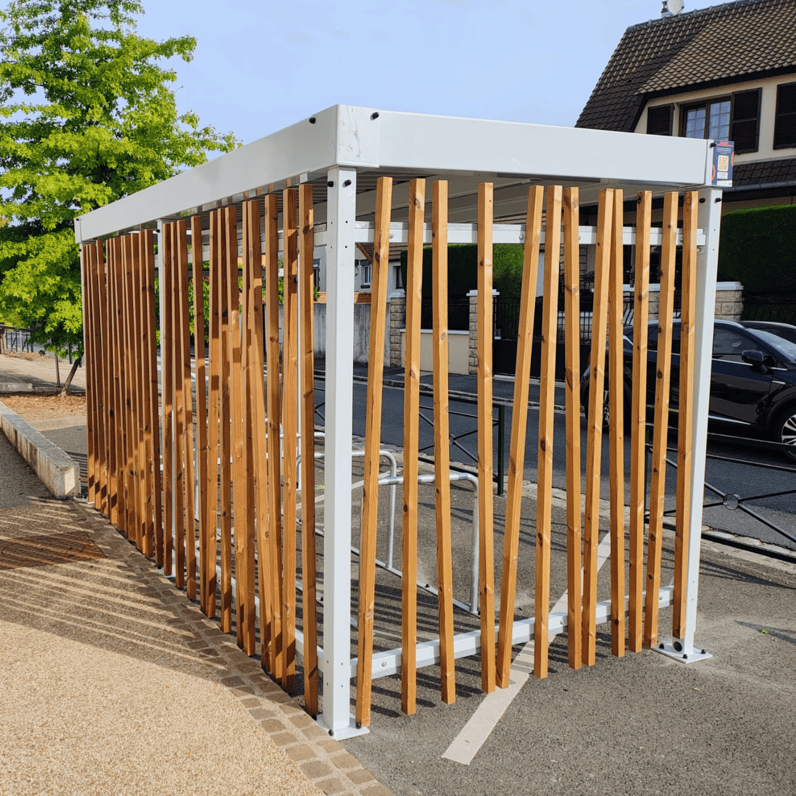 Abri vélo design installé par Bycommute devant une école de la ville de Brunoy, structure moderne en métal avec lames verticales en bois, offrant un espace sécurisé pour stationner les vélos.