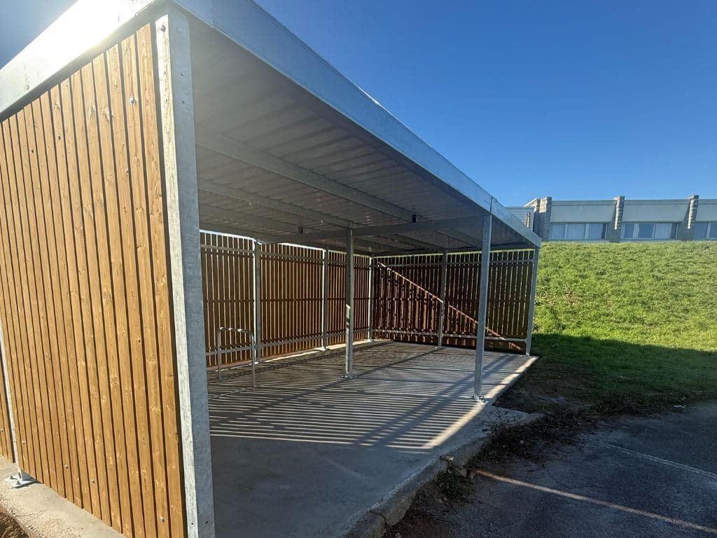 Abri vélo bois ouvert sur l’avant, à structure métallique galvanisée et parois latérales en bois clair.