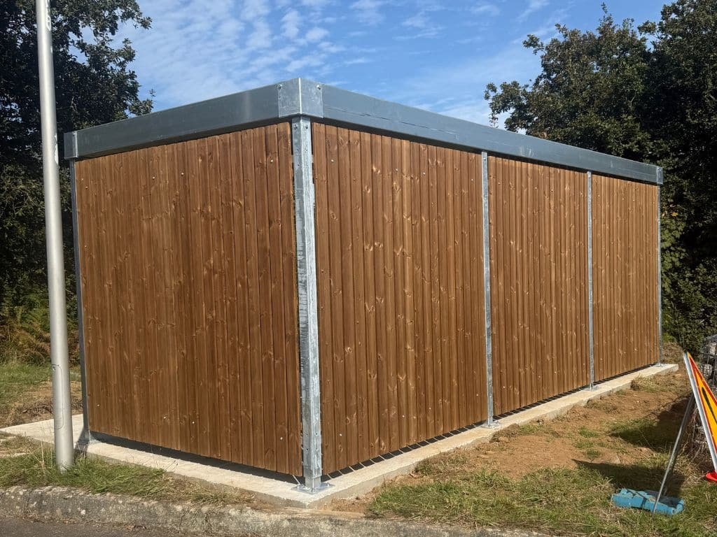 Abri vélo bois fermé avec structure métallique galvanisée et toit plat, installé sur une dalle béton.