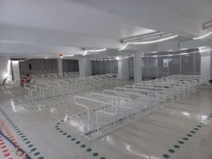 Abri vélo entreprise intérieur moderne avec rangées de supports à vélos métalliques blancs dans un parking sécurisé Bycommute.