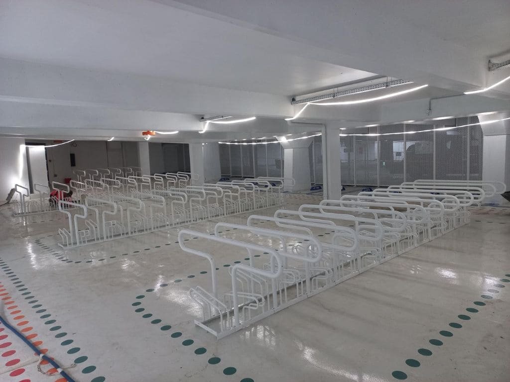 Abri vélo entreprise intérieur moderne avec rangées de supports à vélos métalliques blancs dans un parking sécurisé Bycommute.