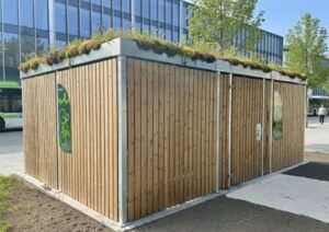 Abri vélo fermé en bois avec toiture végétalisée, installé en zone urbaine, idéal pour les entreprises ou collectivités soucieuses d’esthétique et de développement durable.