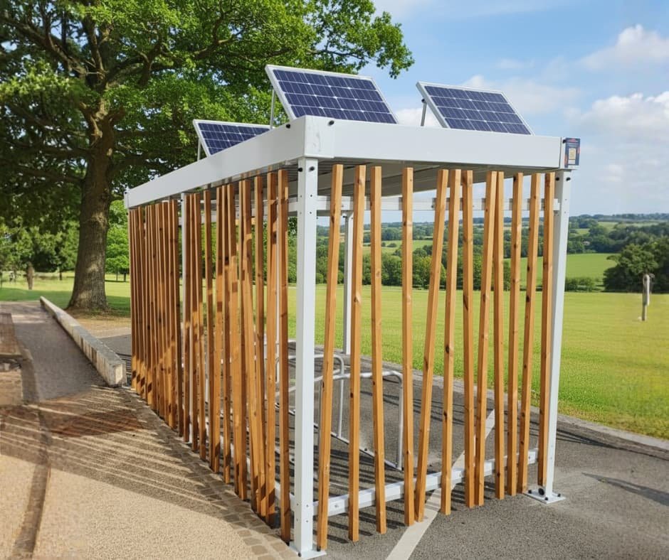 Abri vélo design Bycommute en bois et métal équipé de panneaux solaires sur le toit, installé en extérieur dans un cadre verdoyant, idéal pour entreprises et collectivités.